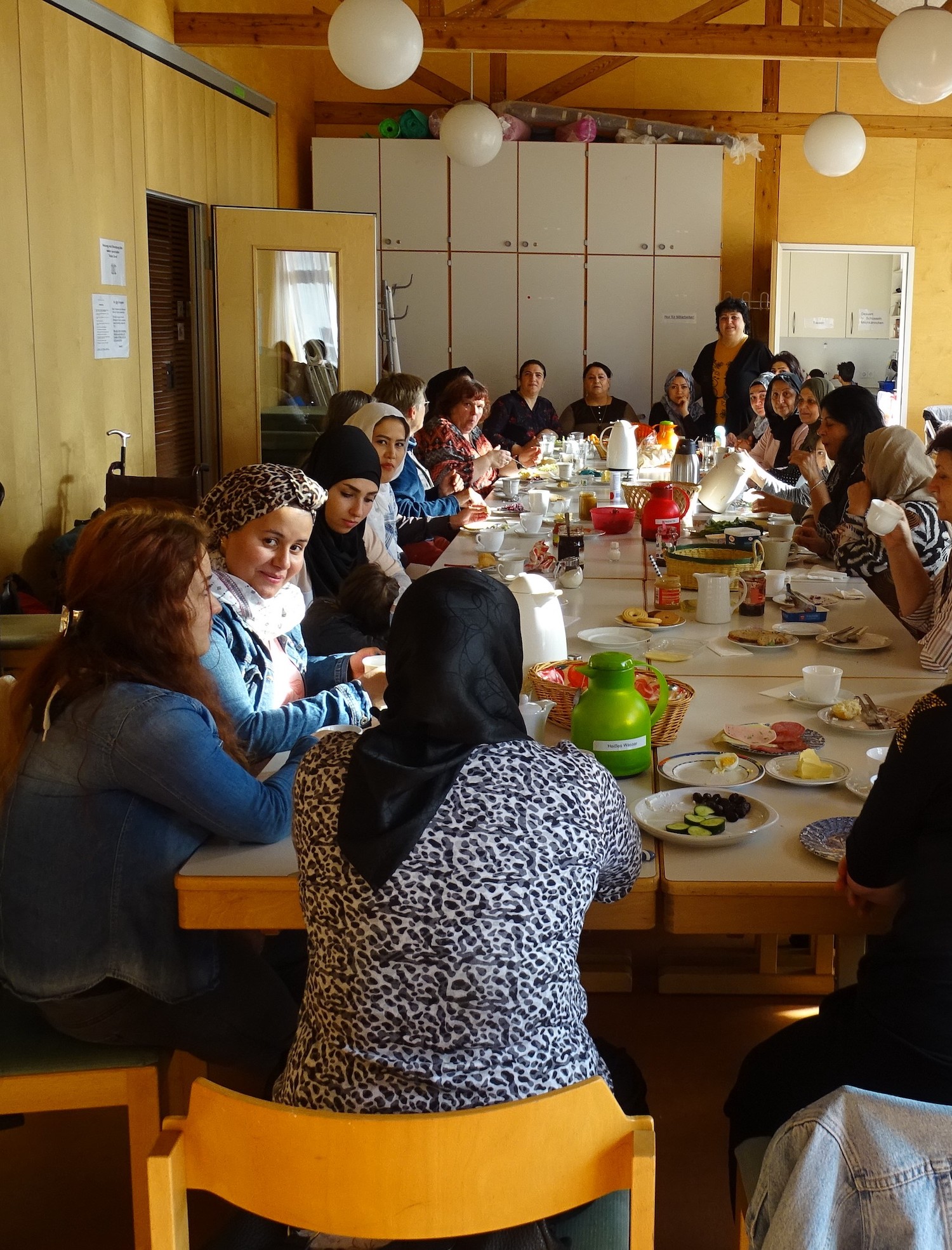 21 Frauen sitzen an einem großen Tisch und frühstücken
