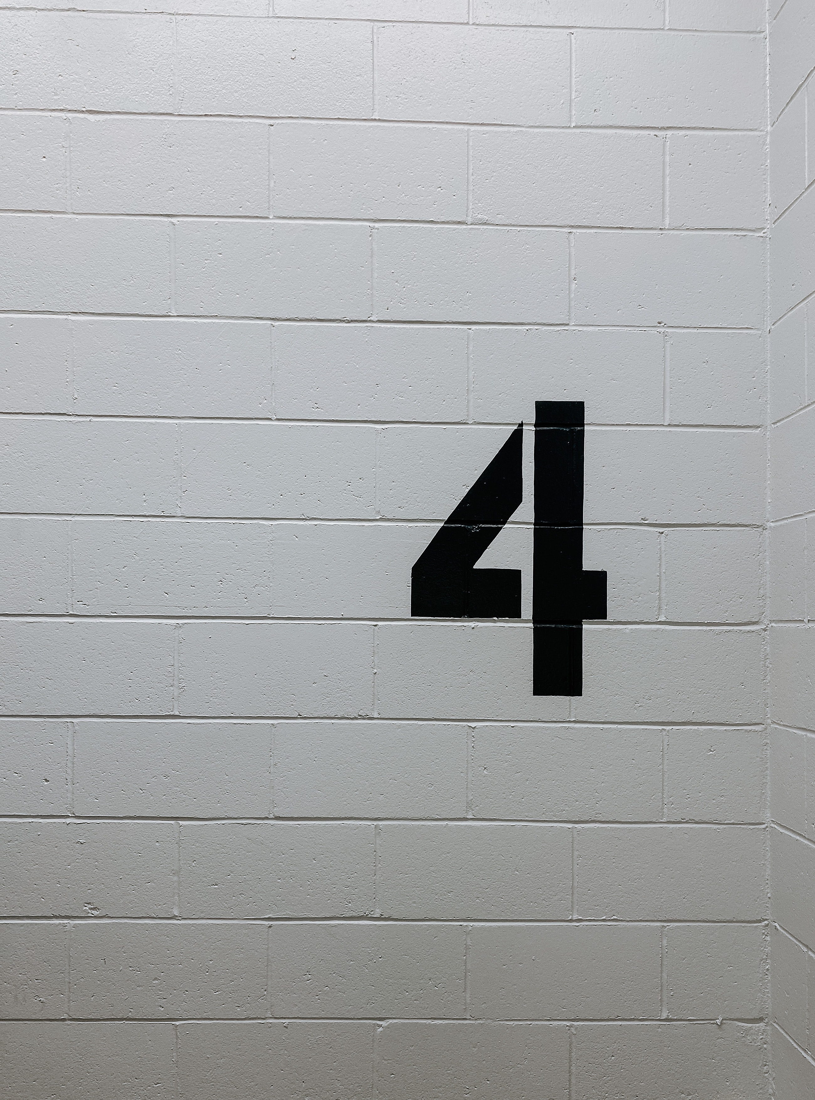 Eine schwarze Vier, die auf eine graue Wand gemalt wurde.