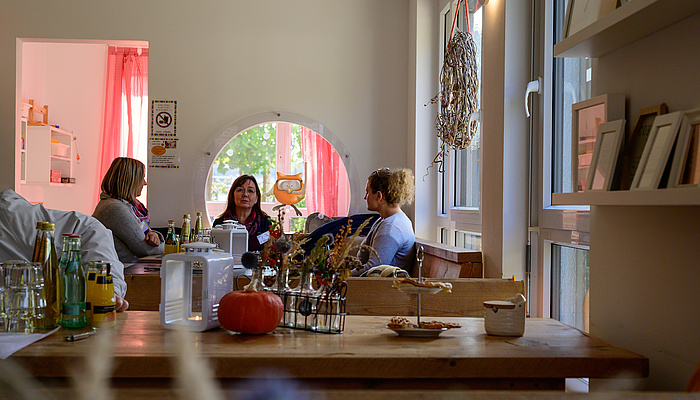 Drei Frauen sitzen an einem Tisch in einem Café und unterhalten sich