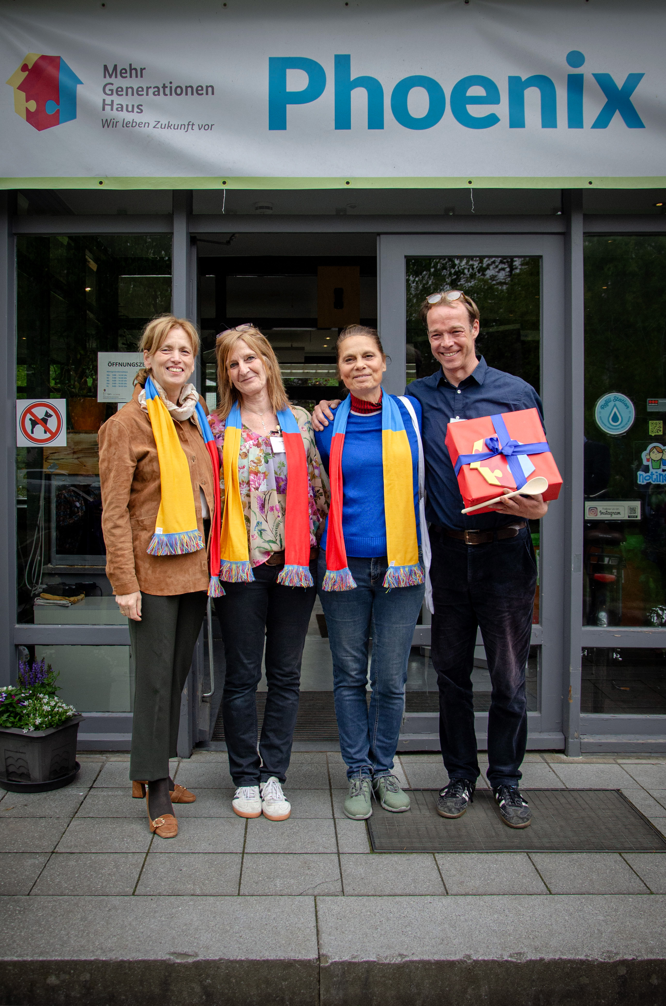drei Frauen und ein Mann stehen vor dem Hauseingang vom Mehrgenerationenhaus Phoenix