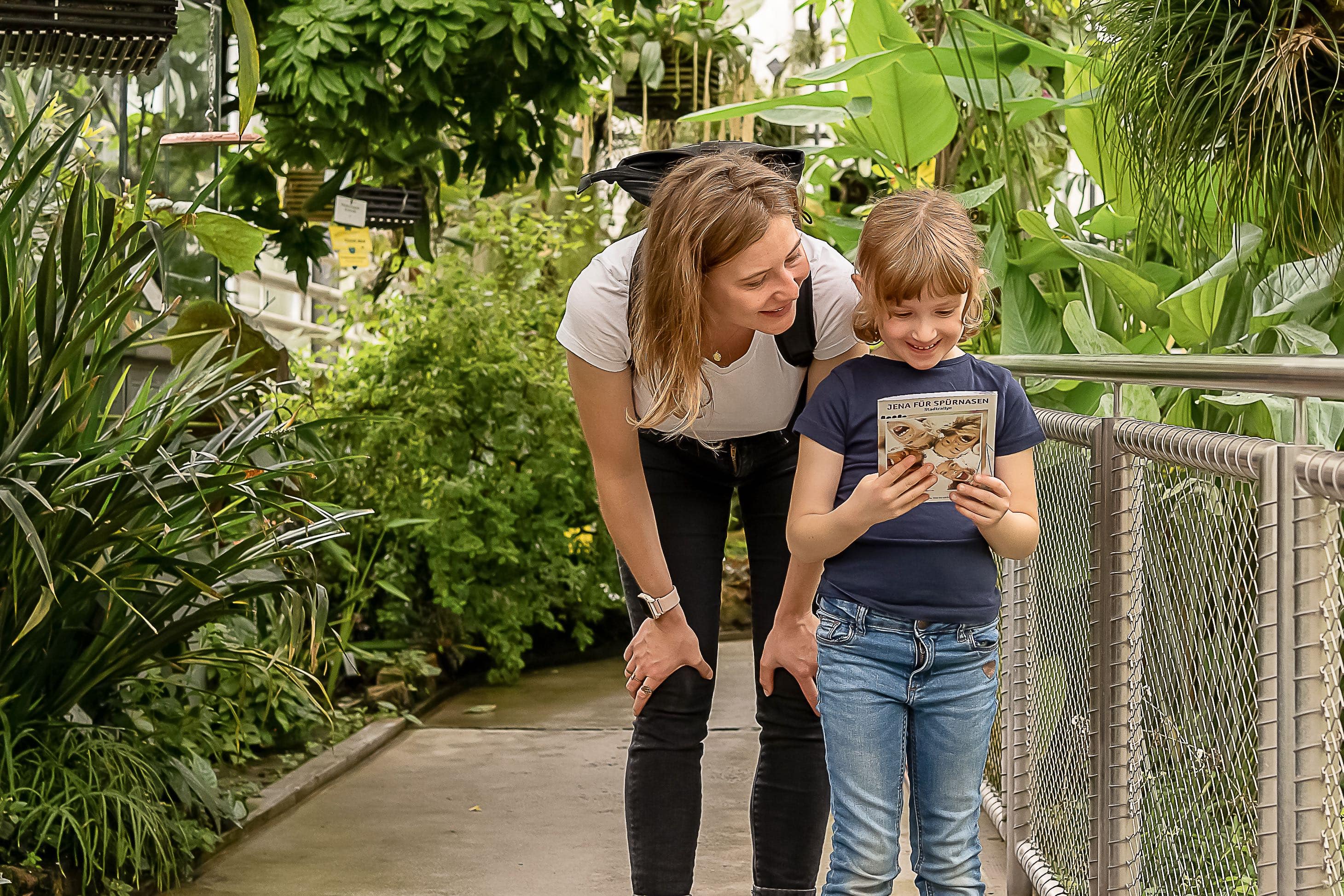 Ein Kind und eine Frau stehen zusammen in einem großen Tropenhaus eines Botanischen Gartens.